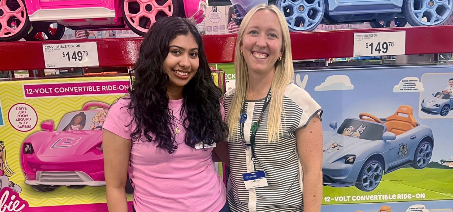 Diana and Krystle smile in front of the toy aisle of Sam's Club